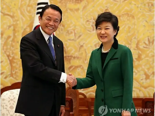 握手を交わす朴大統領と麻生副総理＝25日、ソウル（聯合ニュース）