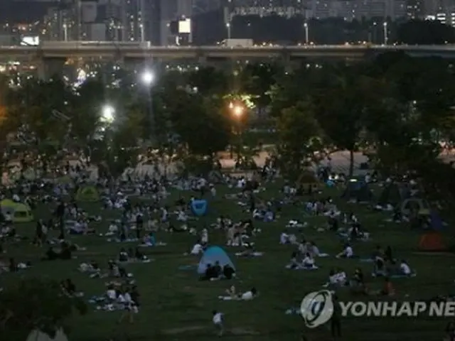 夜になっても気温はなかなか下がらない。漢江沿いで涼を求める市民＝１０日、ソウル（聯合ニュース）