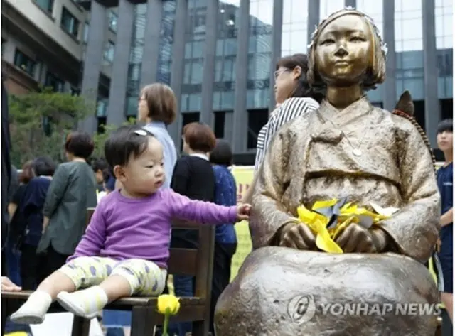 今月６日、日本大使館前で開かれた水曜集会に参加した子どもと少女像＝（聯合ニュース）