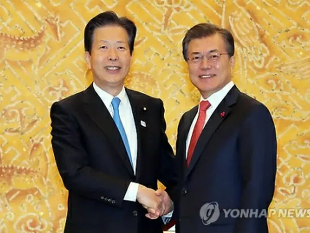 握手を交わす文大統領（右）と山口代表＝２３日、ソウル（聯合ニュース）