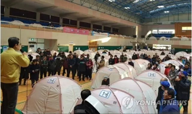 昨年１１月の地震により室内体育館で避難生活をしている市民も今回の余震に不安を募らせた。マイクで状況を説明する浦項市長＝１１日、浦項（聯合ニュース）