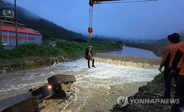 珍島郡の河川に落下した掘削機。周辺に行方不明者がいないか消防隊員が捜索している（全羅南道消防本部提供）＝（聯合ニュース）≪転載・転用禁止≫