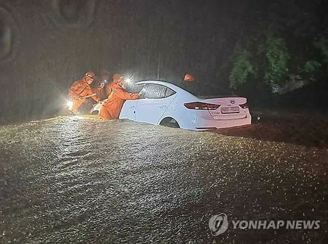 江原道鉄原郡で２２日午後、冠水した道路で立ち往生した車を救助隊が移動させている（江原特別自治道消防本部提供）＝（聯合ニュース）≪転載・転用禁止≫