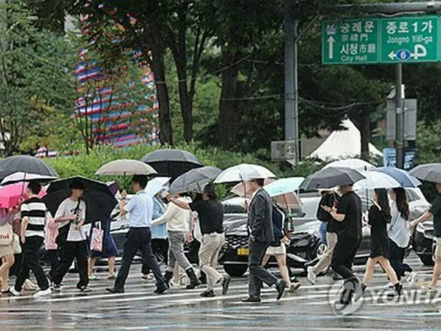 傘を差してソウル・光化門前の交差点をわたる市民ら＝（聯合ニュース）