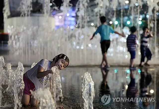 公園の噴水で水遊びする子ども＝１３日、ソウル（聯合ニュース）