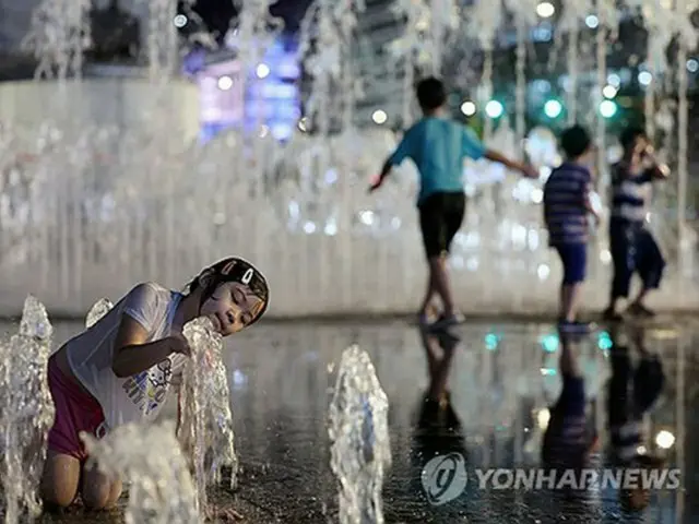 公園の噴水で水遊びする子ども＝１３日、ソウル（聯合ニュース）