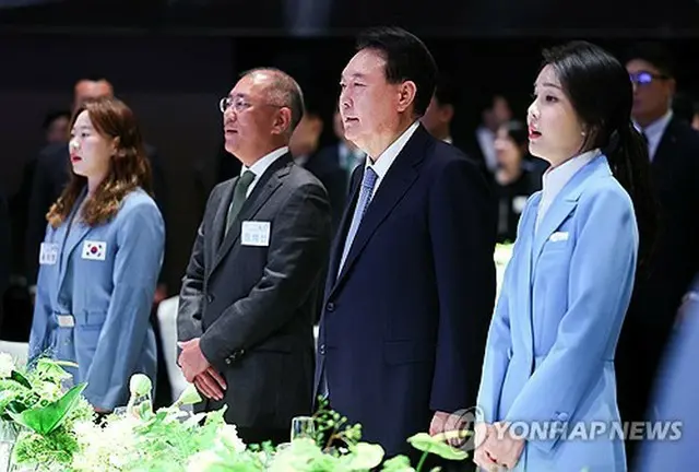 ２２日、パリ五輪韓国選手団を招いてソウル市内のホテルで開かれた夕食会で韓国の国歌「愛国歌」を歌う尹大統領（右から２人目）と鄭氏（同３人目）＝（聯合ニュース）