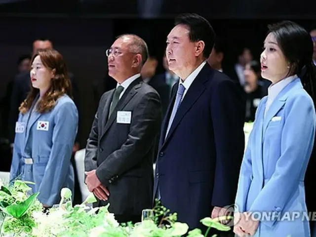 ２２日、パリ五輪韓国選手団を招いてソウル市内のホテルで開かれた夕食会で韓国の国歌「愛国歌」を歌う尹大統領（右から２人目）と鄭氏（同３人目）＝（聯合ニュース）