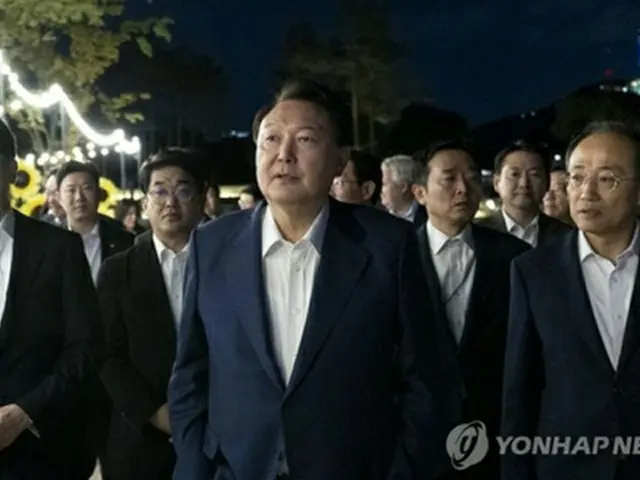 ソウル・竜山の大統領室庁舎前の庭園で開かれた夕食会に出席した尹大統領（中央）と与党「国民の力」の韓東勲代表（左、大統領室提供）＝（聯合ニュース）≪転載・転用禁止≫