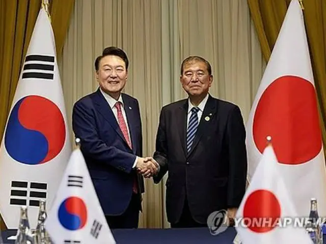 握手を交わす韓国の尹錫悦大統領（左）と日本の石破茂首相＝１６日、リマ（聯合ニュース）