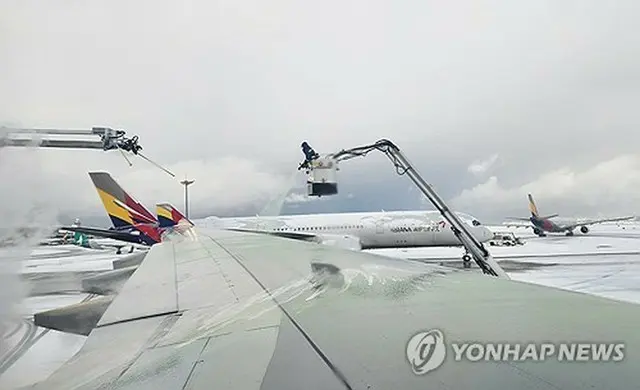 仁川国際空港で機体に積もった雪を溶かす作業が行われている＝２７日、仁川（聯合ニュース）