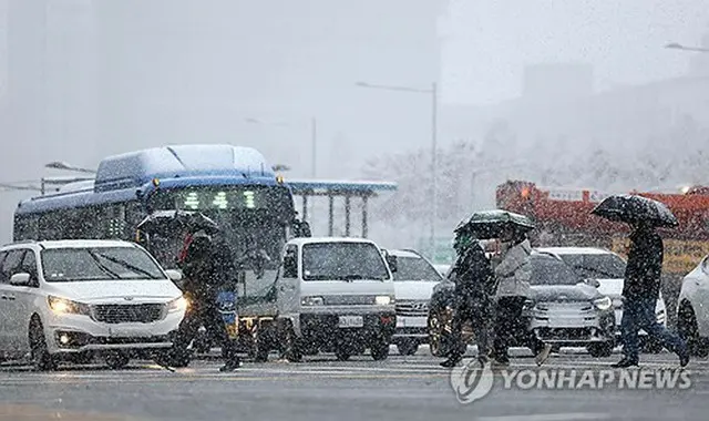 雪の中を歩く市民ら＝２７日、ソウル（聯合ニュース）