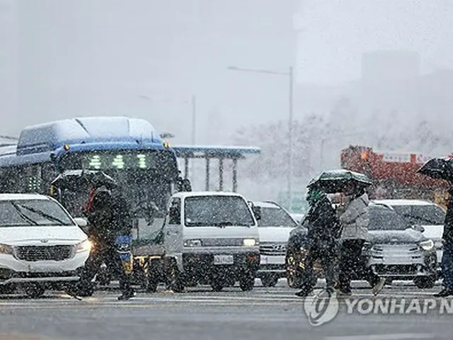 雪の中を歩く市民ら＝２７日、ソウル（聯合ニュース）