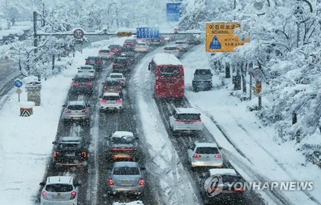 雪道を徐行する車＝２８日、水原（聯合ニュース）